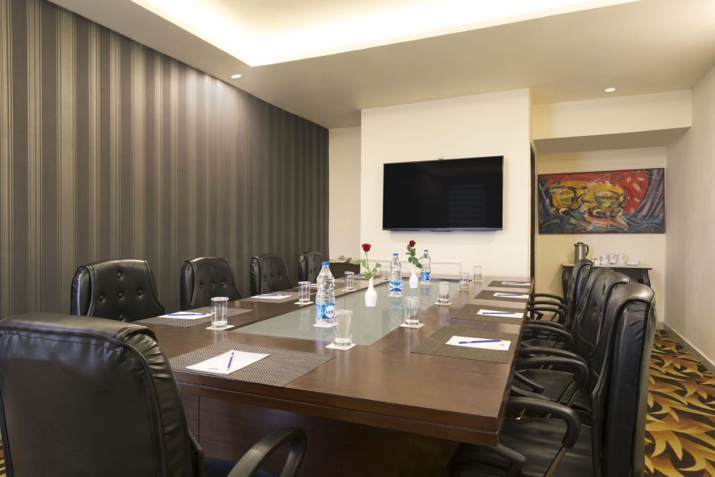 Board Room with a long meeting table, leather chairs, notepads and a wall-mounted screen