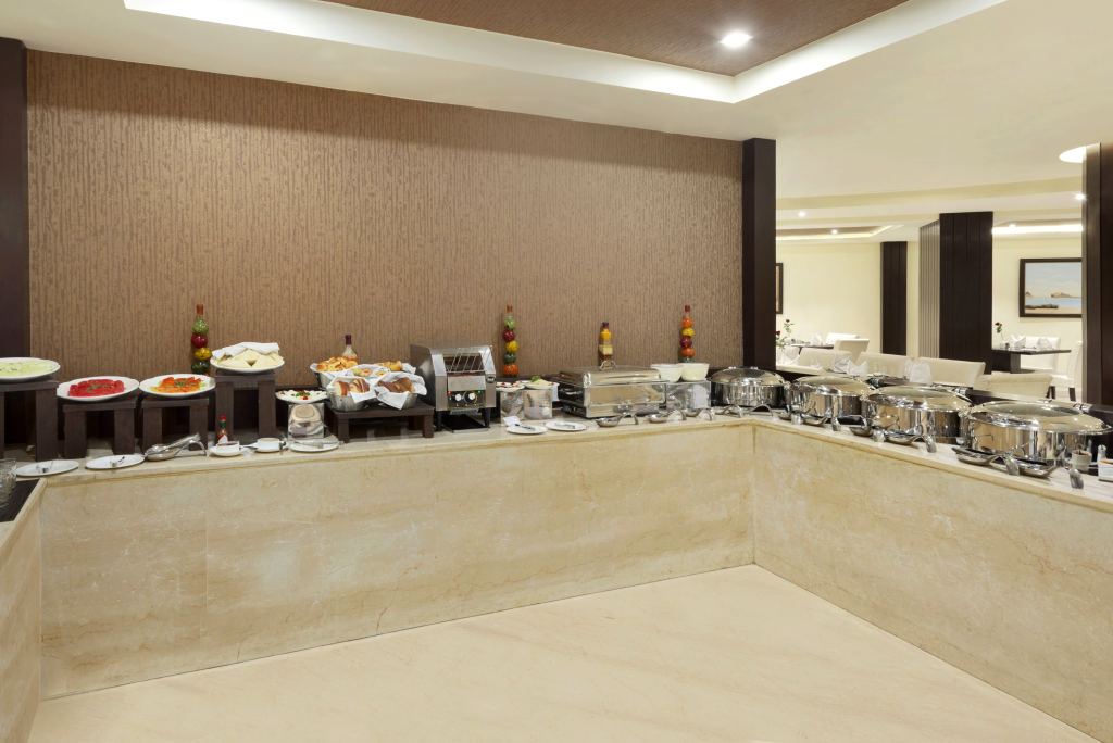 Buffet counter with breads, a toaster, cold platters and covered hot dishes