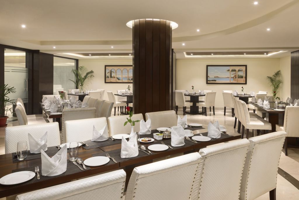 Clouds restaurant dining room with set tables, white upholstered chairs and framed paintings