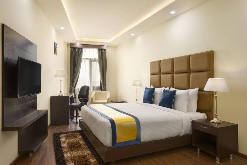 Deluxe Double Room with a double bed, wall-mounted TV, work desk and an armchair by the window