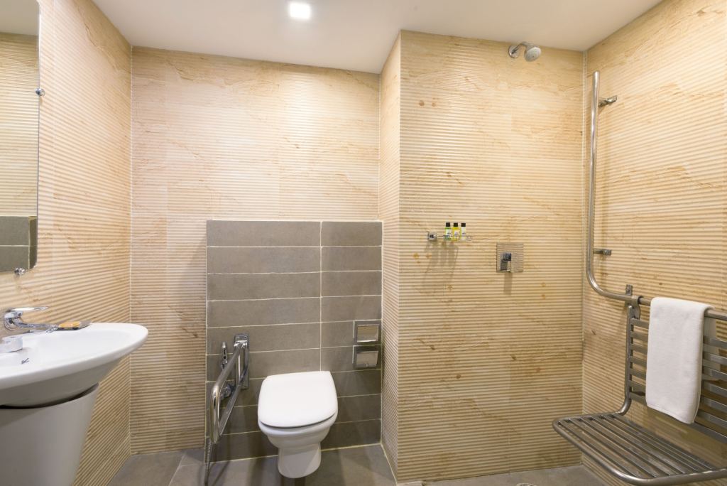 Guest bathroom with a wash basin, grab rails and a walk-in shower with a fold-down seat